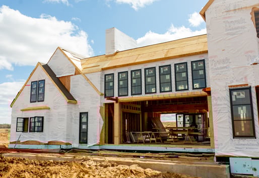 An under-construction home with windows and house wrap installed.