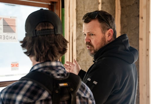 A builder talks to one of his crew while onsite.