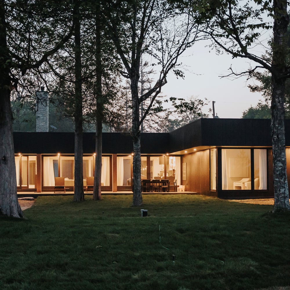 An exterior shot of a home glowing from the inside through floor-to-ceiling A-Series Picture Windows and A-Series Gliding Patio Doors.