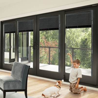boy playing with dog in front of andersen patio doors with between the blinds